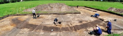 Figure 2. Looking north across the round-house being uncovered in 2014. The larger southeast entranceway can be seen to the right, and the smaller west-southwest entrance to the left. The replica round-house constructed as part of the overall project can just be seen in the upper left (image copyright by author).